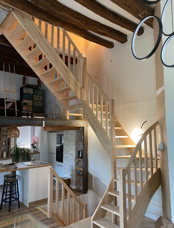 Escalier double quart tournant en hévéa sous des poutres anciennes