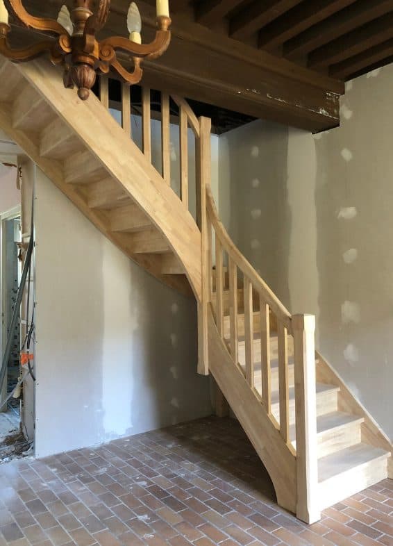 Escalier quart tournant en hévéa sous un plafond à poutres apparentes